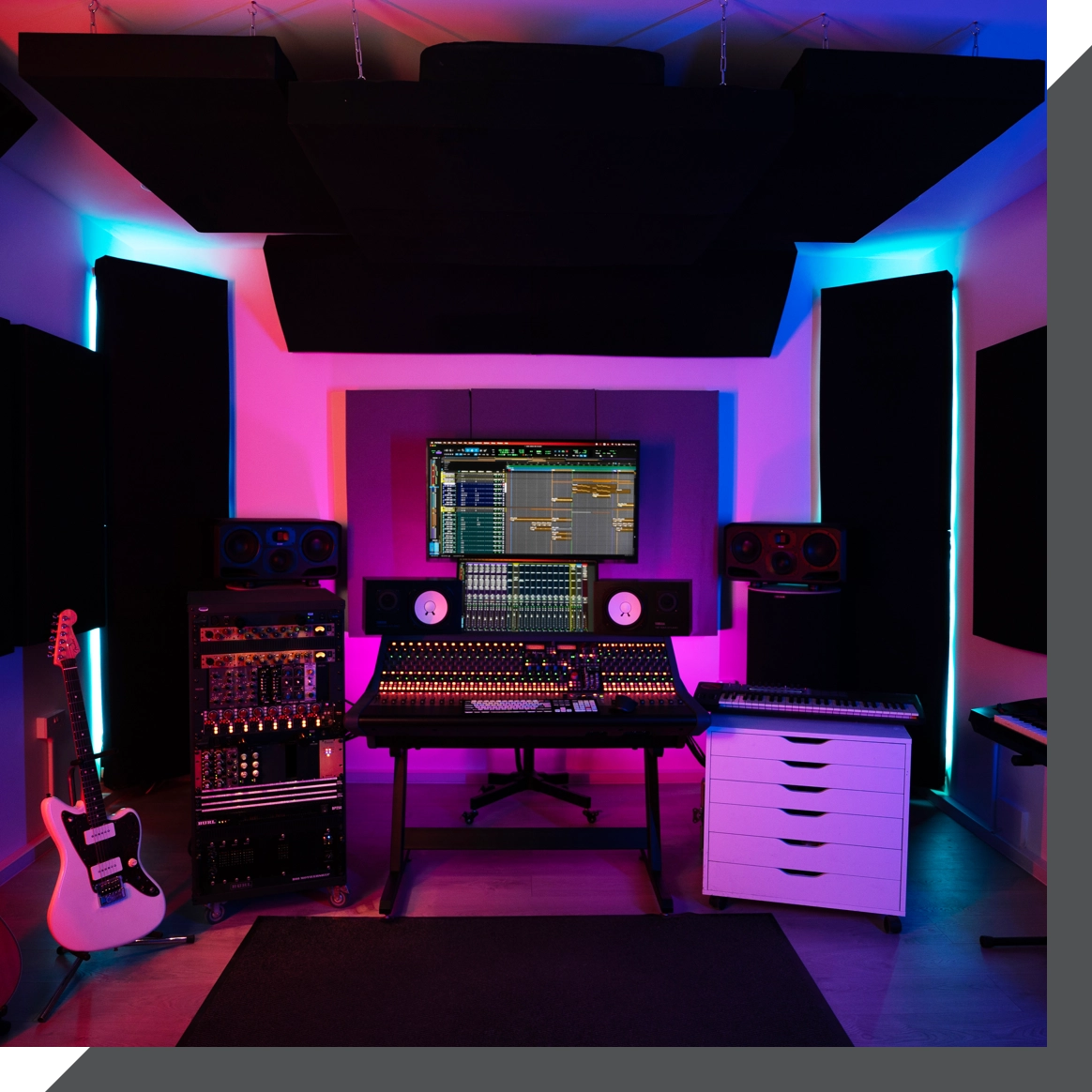 A modern recording studio in London with a central mixing console, dual monitors, and various audio equipment. Two guitars rest on the left, a keyboard on the right, and colored lighting illuminates the space. A window and an air conditioning unit are on the right wall.