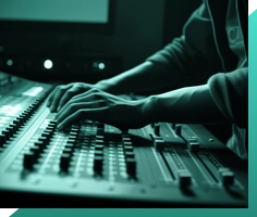A person adjusts knobs and sliders on a mixing console in a dimly lit room. The scene has a greenish tint, emphasizing the focus on the audio equipment.